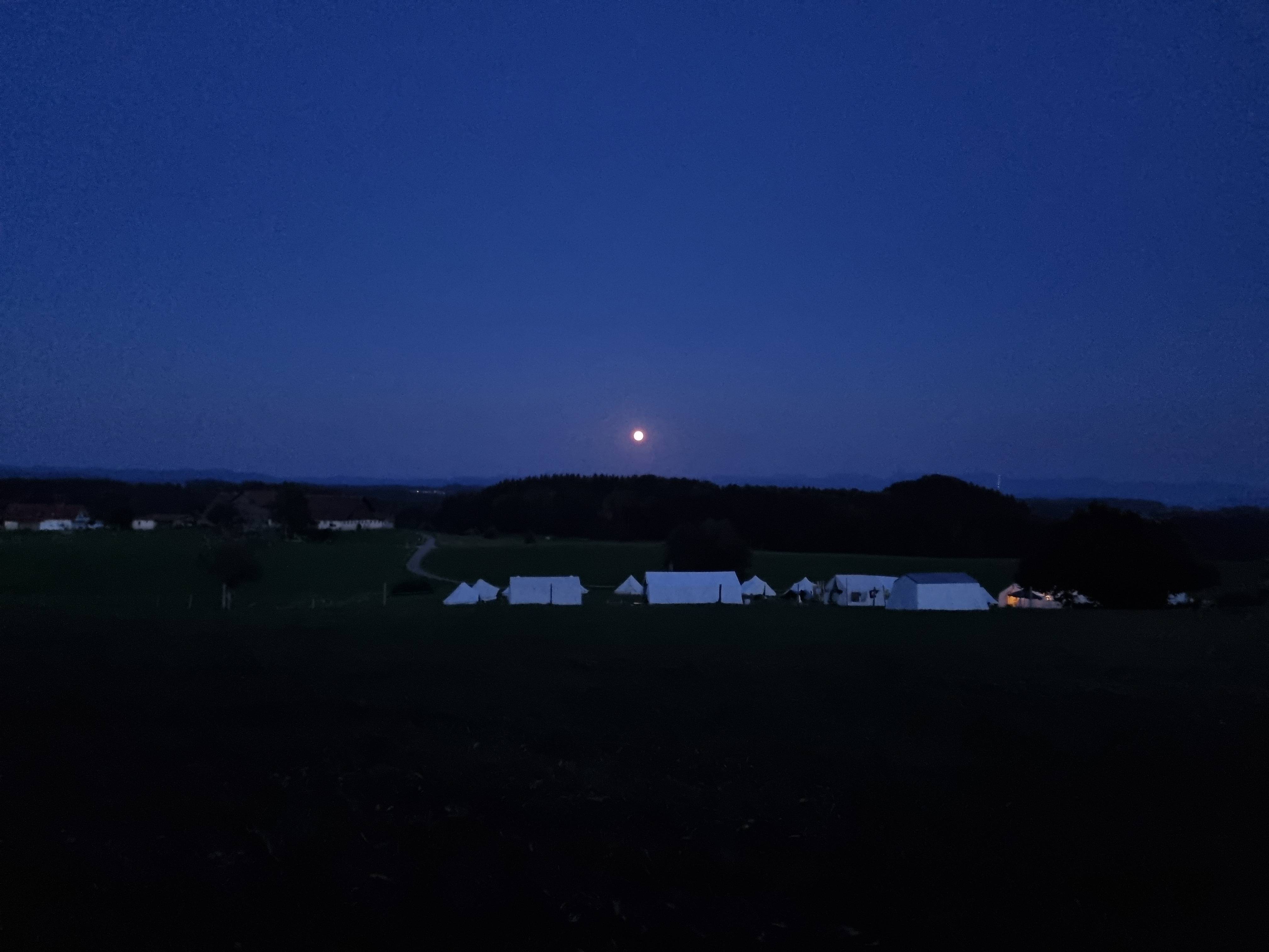 Zeltplatz des Boni-Arche-Camps bei Nacht unter einem klaren Mondhimmel, umgeben von dunkler Landschaft.